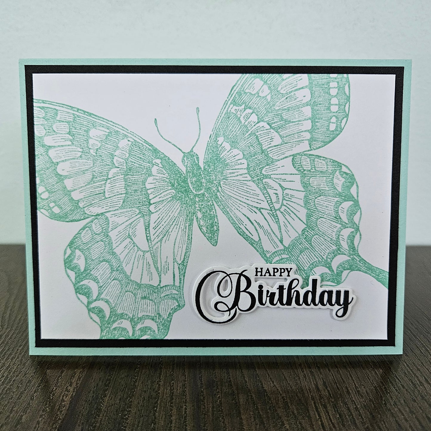 Handmade vintage butterfly birthday card with large sage green stamped butterfly and elegant Happy Birthday sentiment on white inner panel with black and mint border.