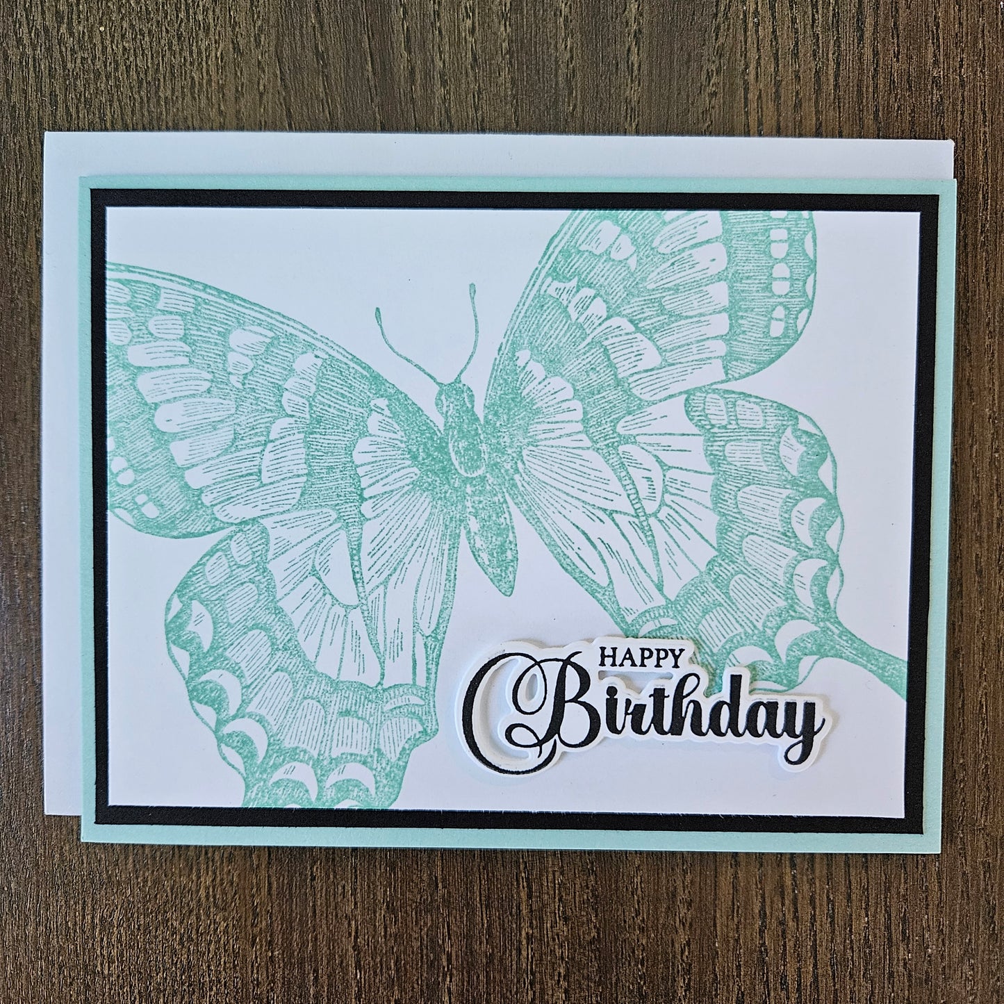 Handmade vintage butterfly birthday card with large sage green stamped butterfly and elegant Happy Birthday sentiment on white inner panel with black and mint border.