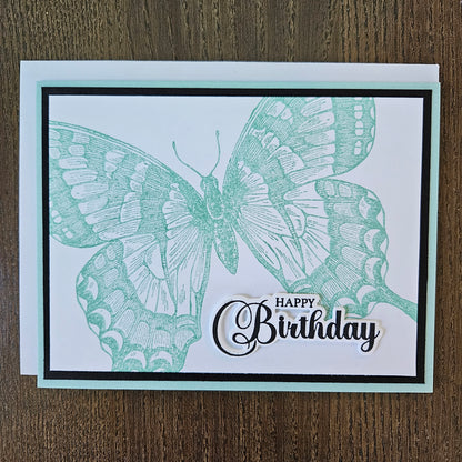 Handmade vintage butterfly birthday card with large sage green stamped butterfly and elegant Happy Birthday sentiment on white inner panel with black and mint border.