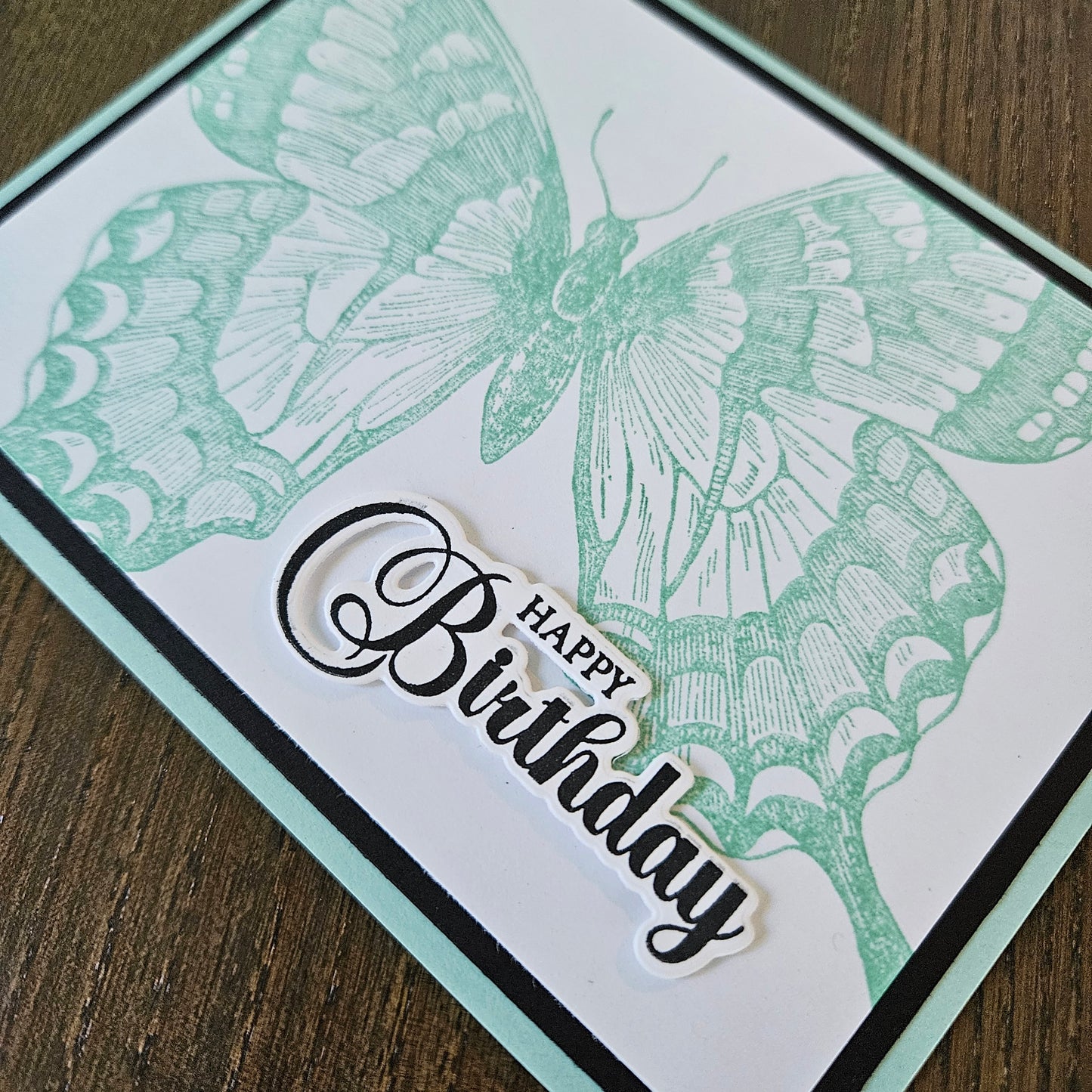 Greeting card with butterfly design and 'Happy Birthday' text on a wooden surface