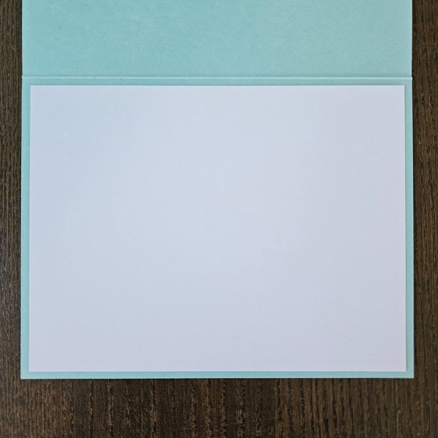 Light blue card with white interior on a wooden surface