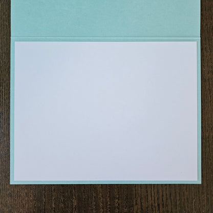 Light blue card with white interior on a wooden surface