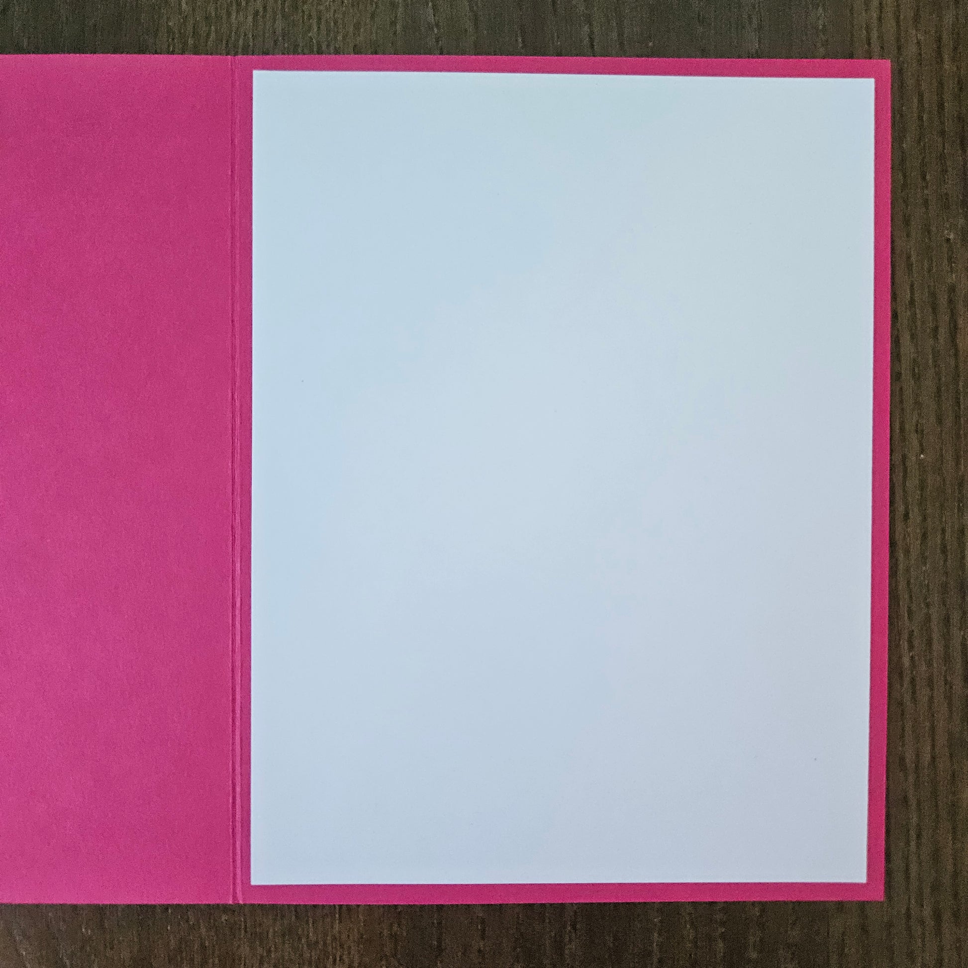 Pink card with a white interior on a wooden surface