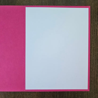 Pink card with a white interior on a wooden surface