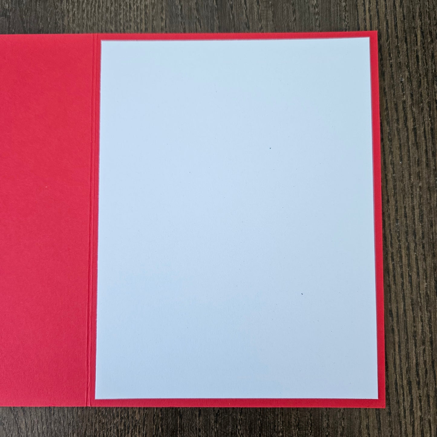 Red card with a white square in the center on a wooden surface
