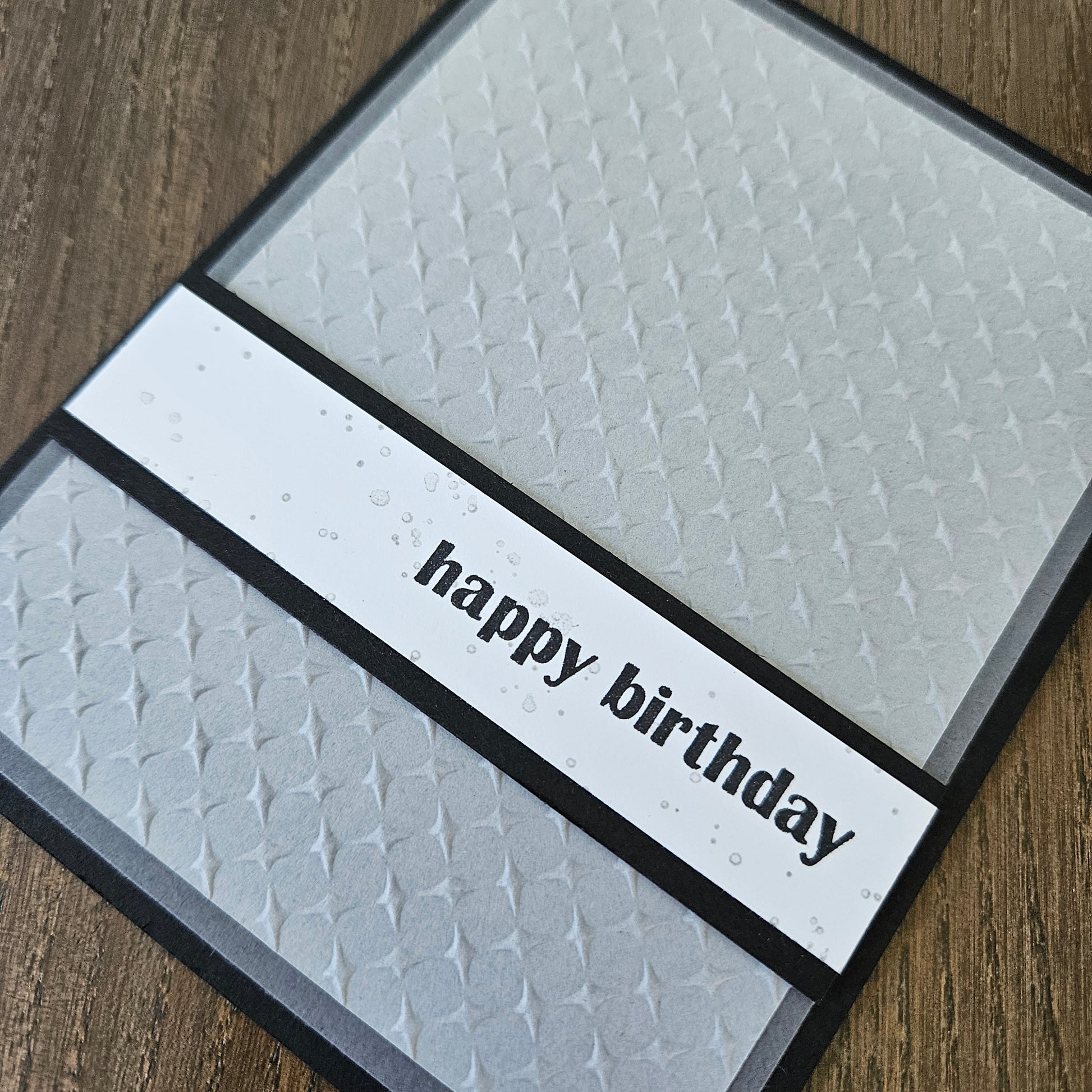 Textured birthday card with 'happy birthday' on a wooden surface