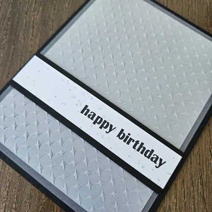 Textured birthday card with 'happy birthday' on a wooden surface
