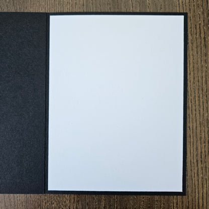 White sheet of paper in a black frame on a wooden surface