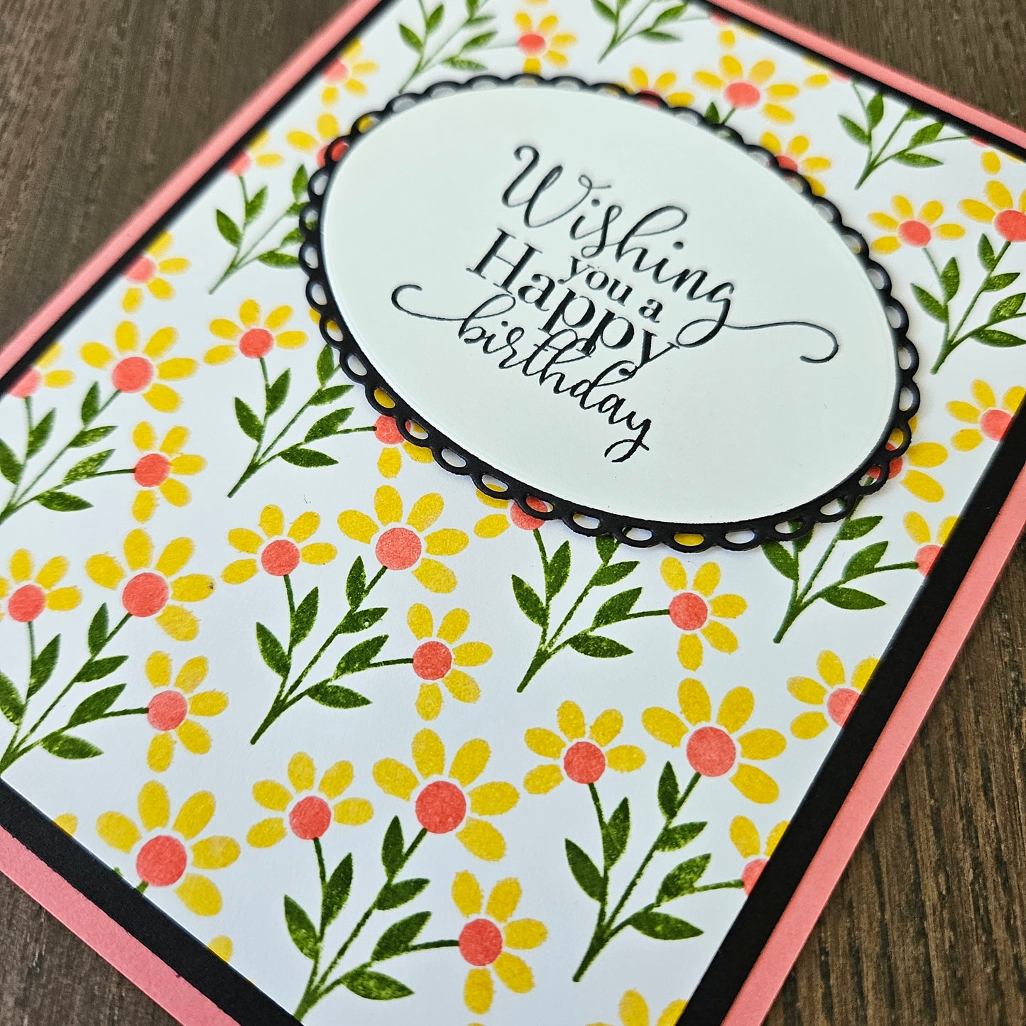 Floral birthday card with 'Wishing you a happy birthday' text on a wooden surface