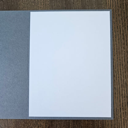 Gray envelope with a white interior on a wooden surface