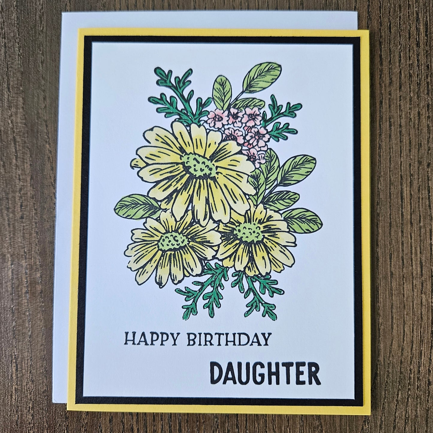 Handmade birthday card for daughter featuring a hand-colored cluster of yellow daisies and tiny pink flowers on a layered white, black, and bright yellow cardstock frame. Bold text reads HAPPY BIRTHDAY DAUGHTER.