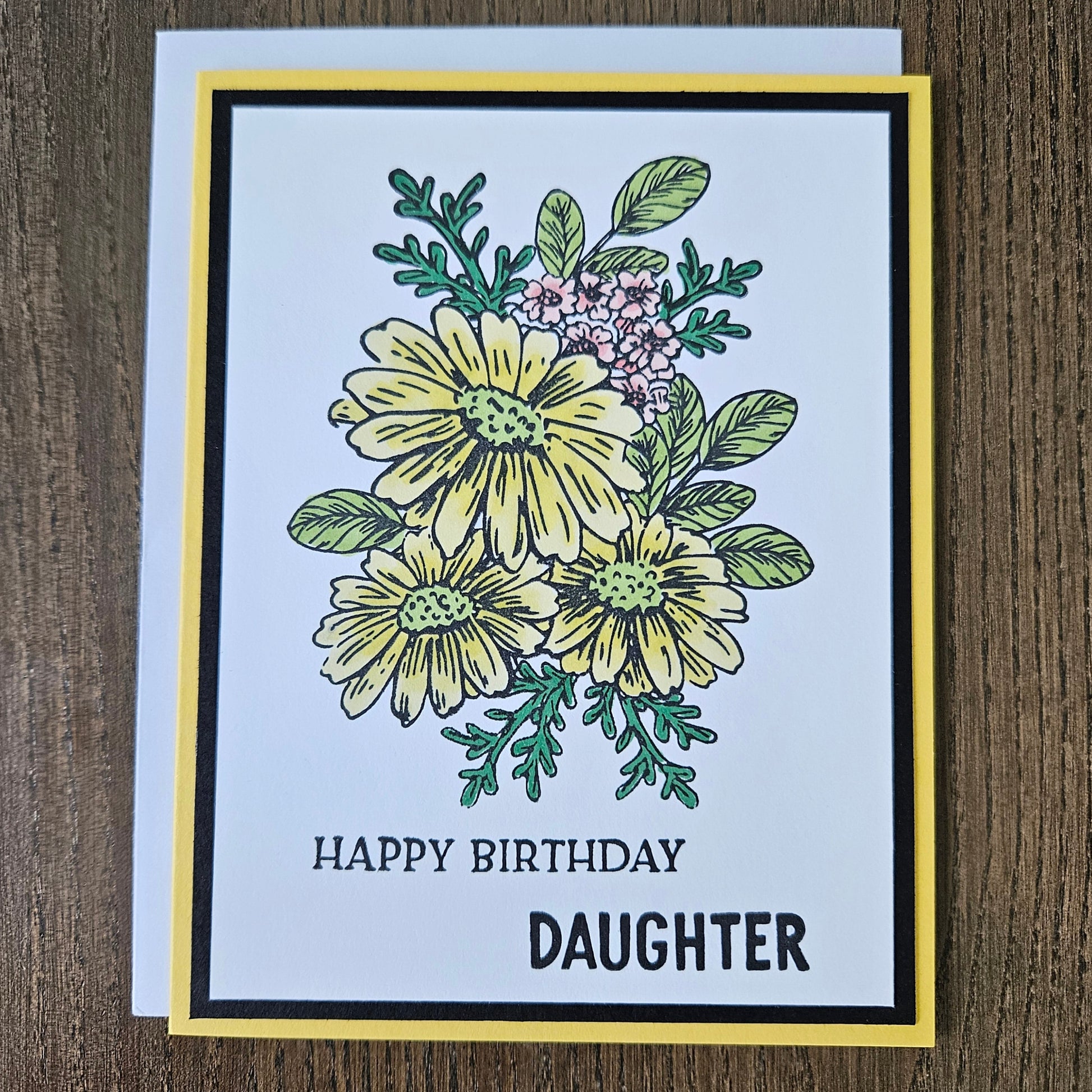 Handmade birthday card for daughter featuring a hand-colored cluster of yellow daisies and tiny pink flowers on a layered white, black, and bright yellow cardstock frame. Bold text reads HAPPY BIRTHDAY DAUGHTER.