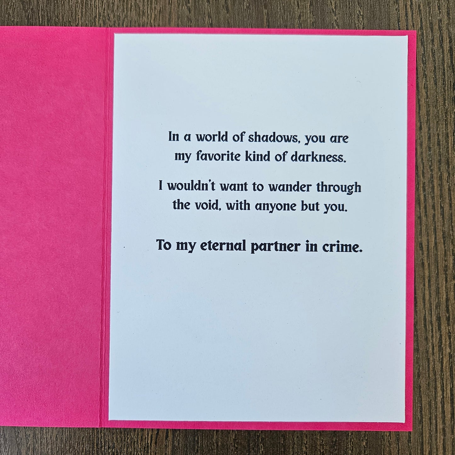 Card with text on a pink border against a wooden background