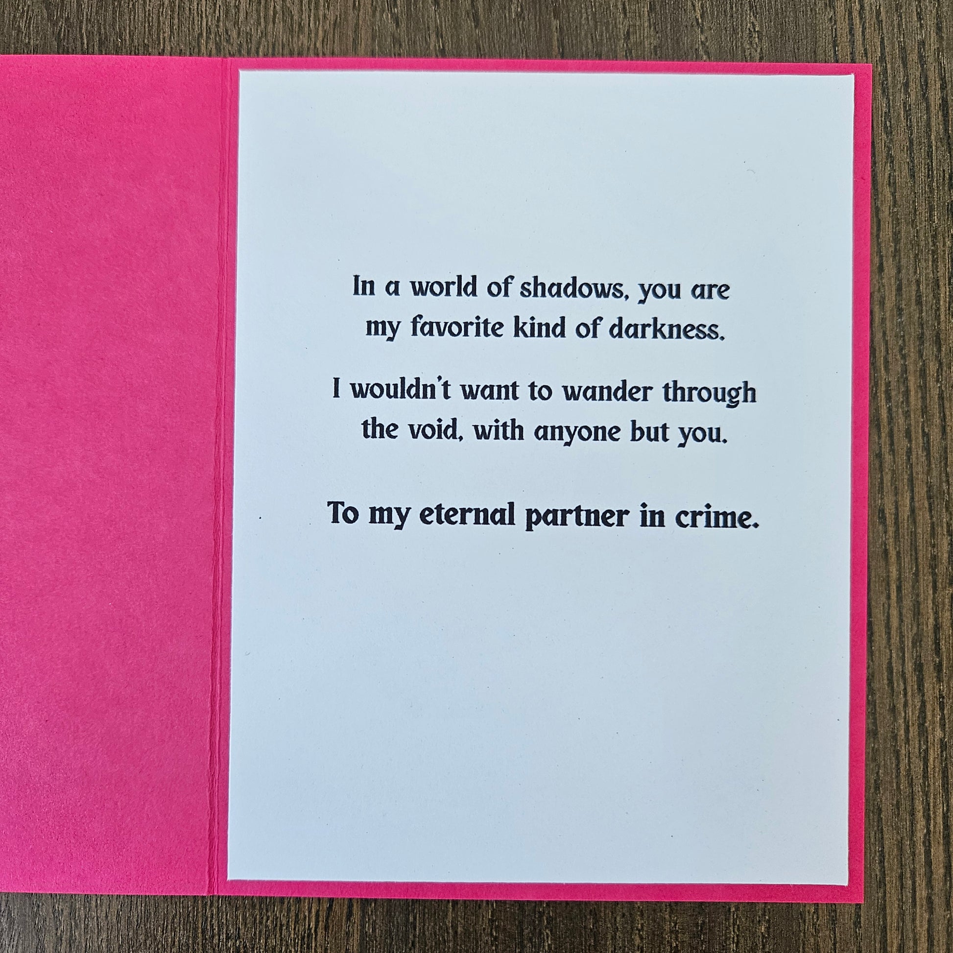 Card with text on a pink border against a wooden background