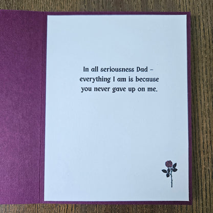 Greeting card with a message to a father on a wooden surface