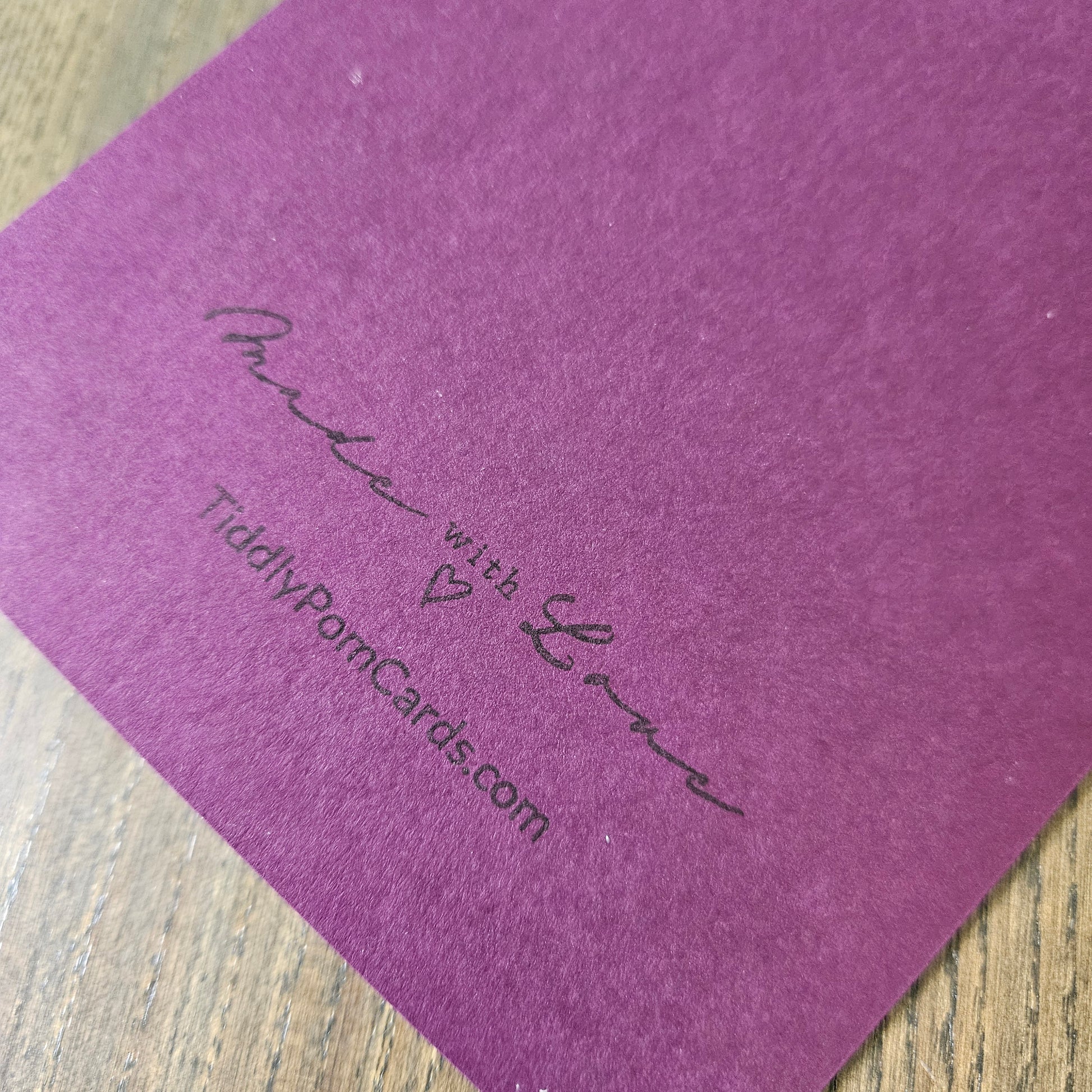 Purple card with 'Made with Love' text and website URL on a wooden surface