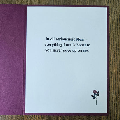 Greeting card with a message and a rose on a wooden surface