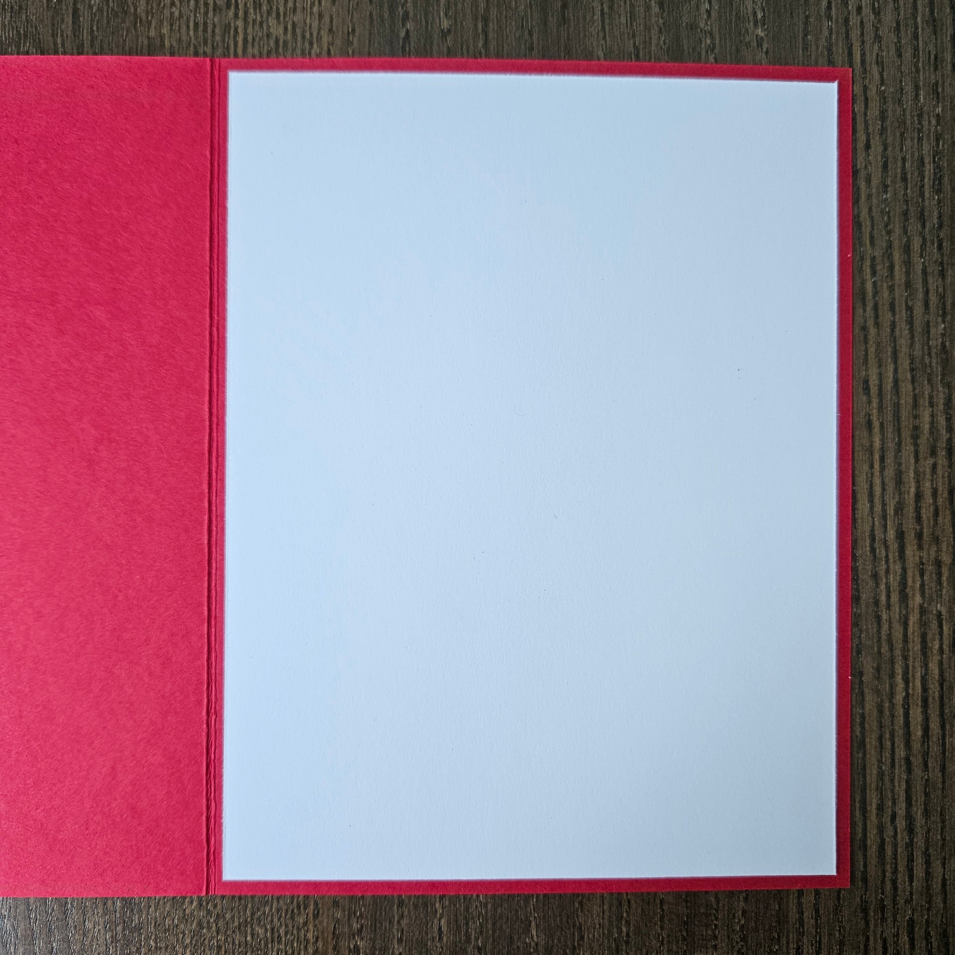 Red envelope with a white card inside on a wooden surface