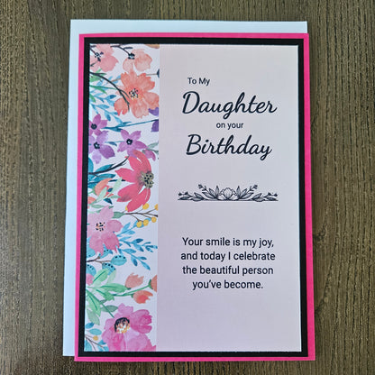 a handmade 5x7 birthday card featuring a vibrant watercolor floral split panel design and printed heartfelt sentiments, finished with a crisp black mat and bright pink cardstock frame. Tiddly Pom Cards