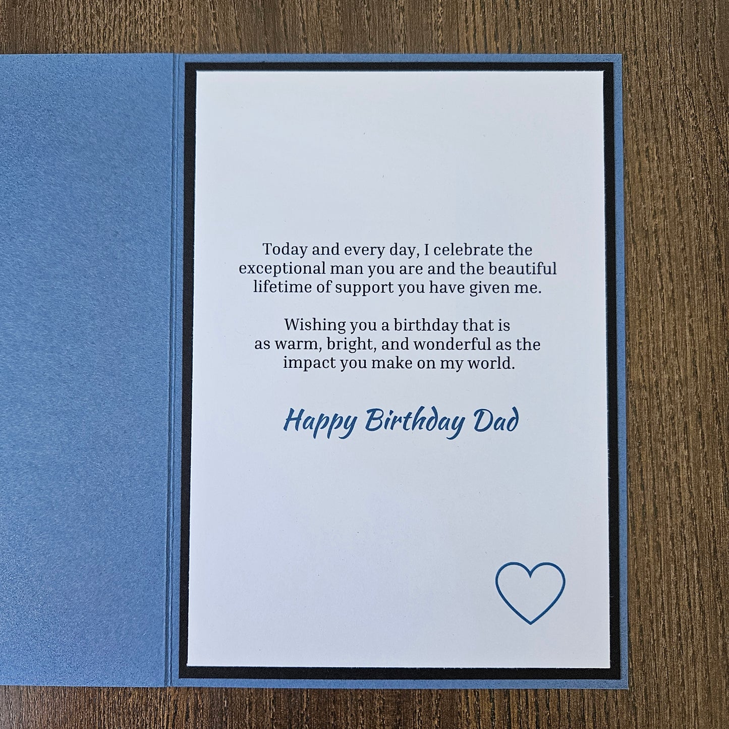 Inside panel of the 5x7 card displaying a printed birthday message in crisp black ink with Happy Birthday Dad in blue script, accented by a single blue heart outline in the lower right corner.