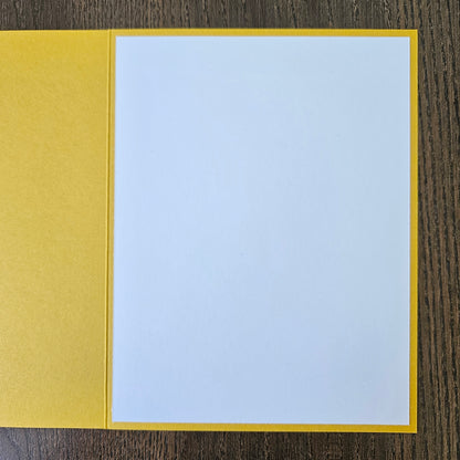 a handmade A2 birthday card featuring a classic black ink storybook sketch illustration of Winnie the Pooh sitting on the grass next to a large honey pot with a balloon floating behind him, printed with the sentiment Sweet little smiles on your birthday, finished with a stitched edge border, red mat, and bright yellow cardstock frame