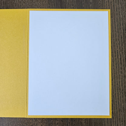 A blank white card or paper sheet with a yellow border, placed on a dark wood surface.