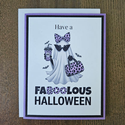 Front of a handmade A2 Halloween card featuring a layered purple and black border around a fashionable ghost wearing a purple leopard bow and sunglasses, holding an iced coffee and purse, with text reading Have a FABOOLOUS HALLOWEEN.