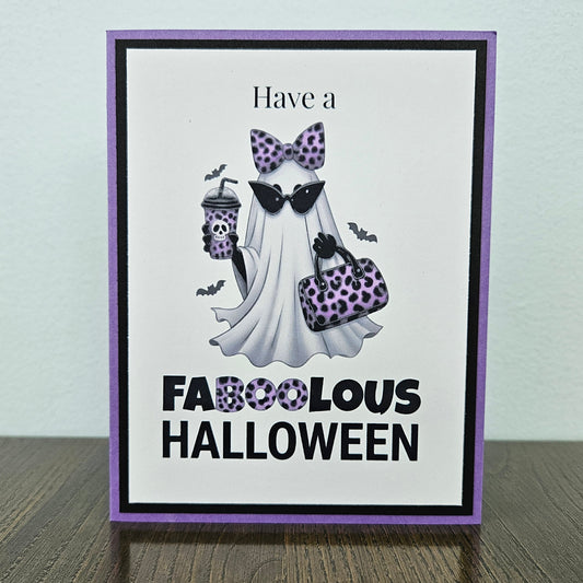 Front of a handmade A2 Halloween card featuring a layered purple and black border around a fashionable ghost wearing a purple leopard bow and sunglasses, holding an iced coffee and purse, with text reading Have a FABOOLOUS HALLOWEEN.