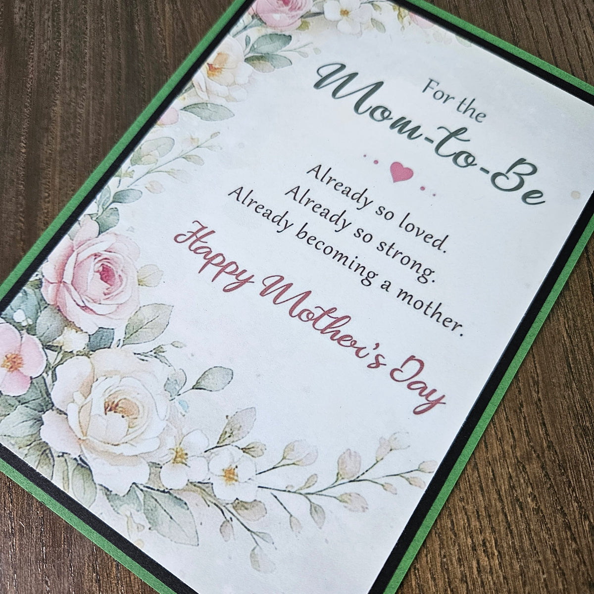 Front of a handmade A2 First Mother's Day card for an expecting mom featuring cream and pink roses framed by green and black borders with text reading To the Mom to Be Happy First Mother's Day.