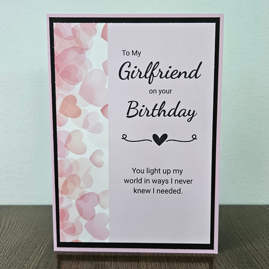 Front of a handmade A2 romantic birthday card for girlfriend featuring a layered pink heart design with text reading You light up my world in ways I never knew I needed.
