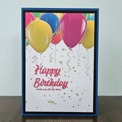 Front of a handmade A2 neutral birthday card featuring colorful balloons and gold confetti framed with layered borders and text reading Happy Birthday.
