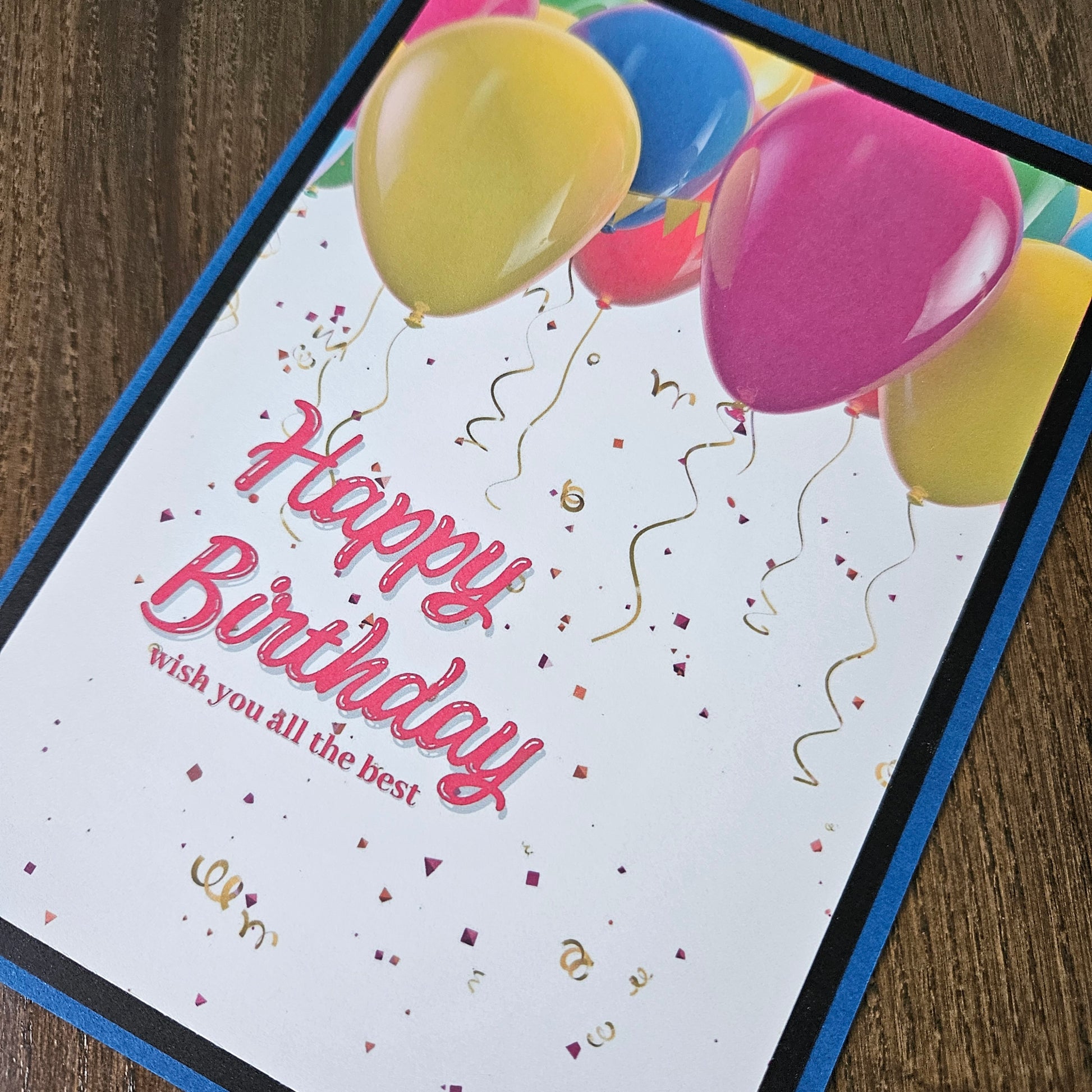 Front of a handmade A2 neutral birthday card featuring colorful balloons and gold confetti framed with layered borders and text reading Happy Birthday.