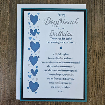 Front of a handmade 5x7 birthday card for boyfriend featuring a vertical row of watercolor blue hearts framed in black and teal with a detailed romantic birthday poem.