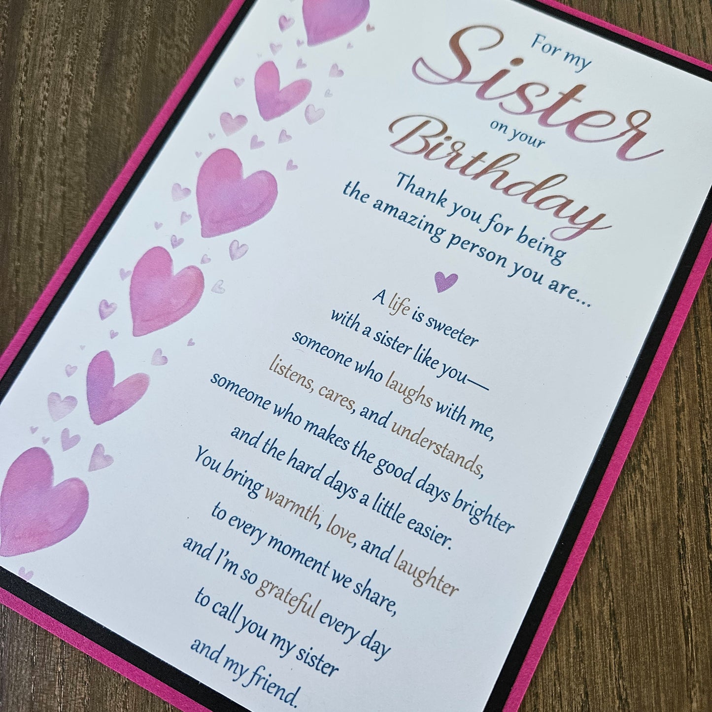 Front of a handmade 5x7 birthday card for sister featuring a vertical row of watercolor pink hearts framed in black and magenta with a detailed birthday poem.