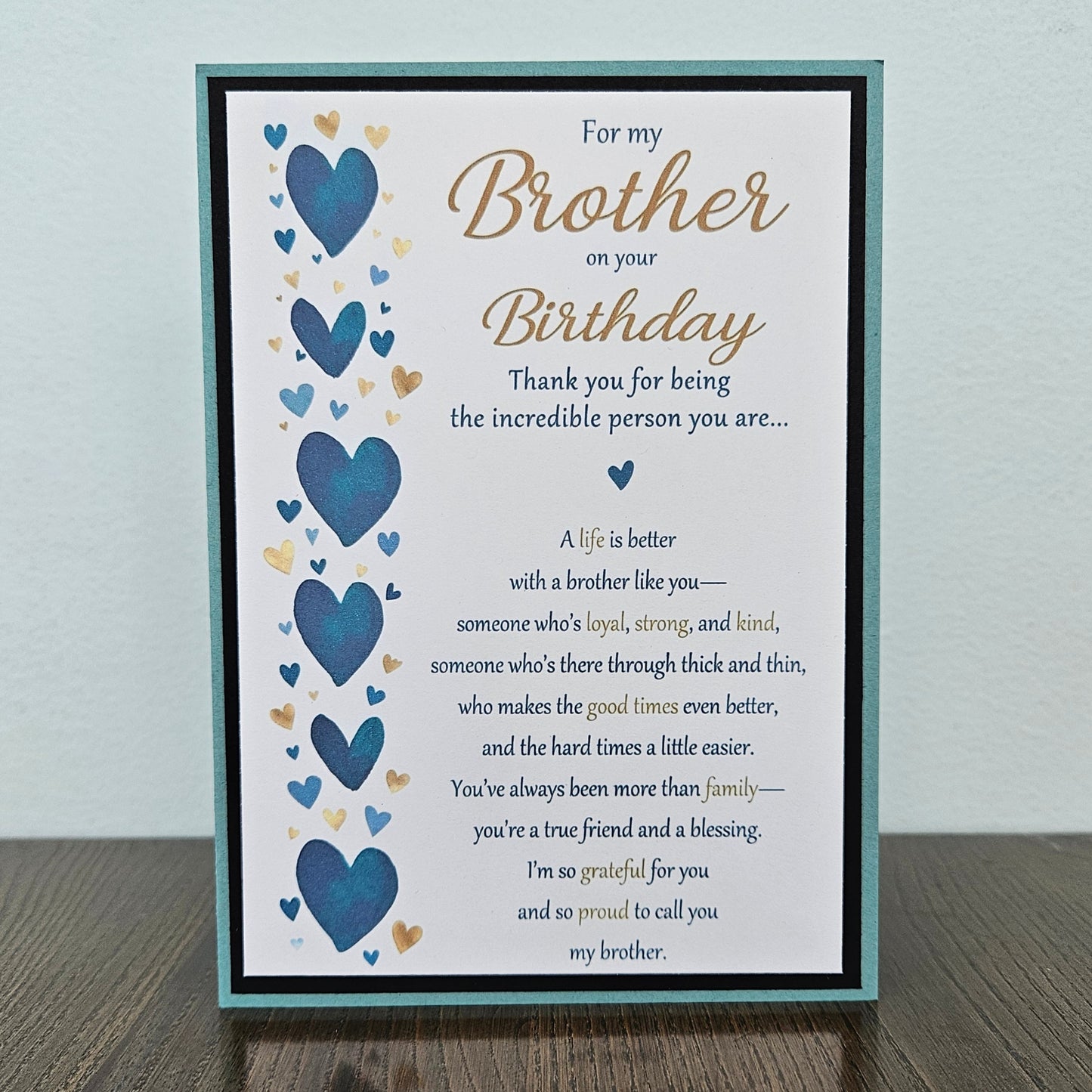Front of a handmade 5x7 birthday card for brother featuring a vertical row of watercolor blue and gold hearts framed in black and teal with a detailed birthday poem.