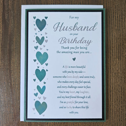 Front of a handmade 5x7 romantic birthday card for husband featuring a vertical row of teal hearts and layered green and black cardstock with printed text reading For my Husband on your Birthday.