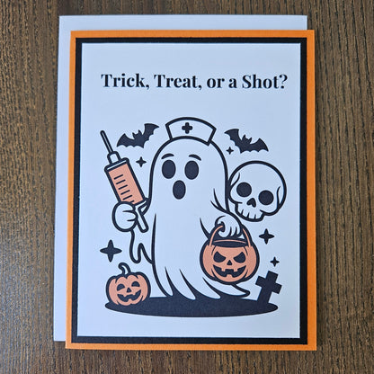 A square Halloween greeting card with an orange and black border, featuring a cartoon ghost holding a syringe and a jack-o'-lantern bucket, with the text 'Trick, Treat, or a Shot?' on a wooden tabletop.