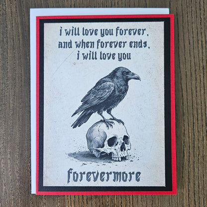 A square greeting card with a gothic design featuring a raven perched on a skull, with the text 'i will love you forever, and when forever ends, i will love you' and 'forevermore', displayed on a wooden surface.