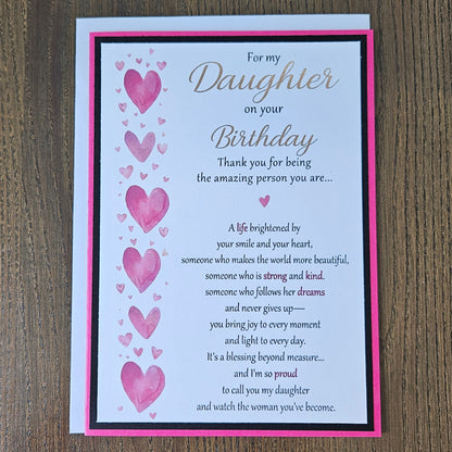 Front view of a handmade 5x7 birthday card for daughter featuring pink watercolor hearts, bold black and hot pink borders, and printed sentimental verses.