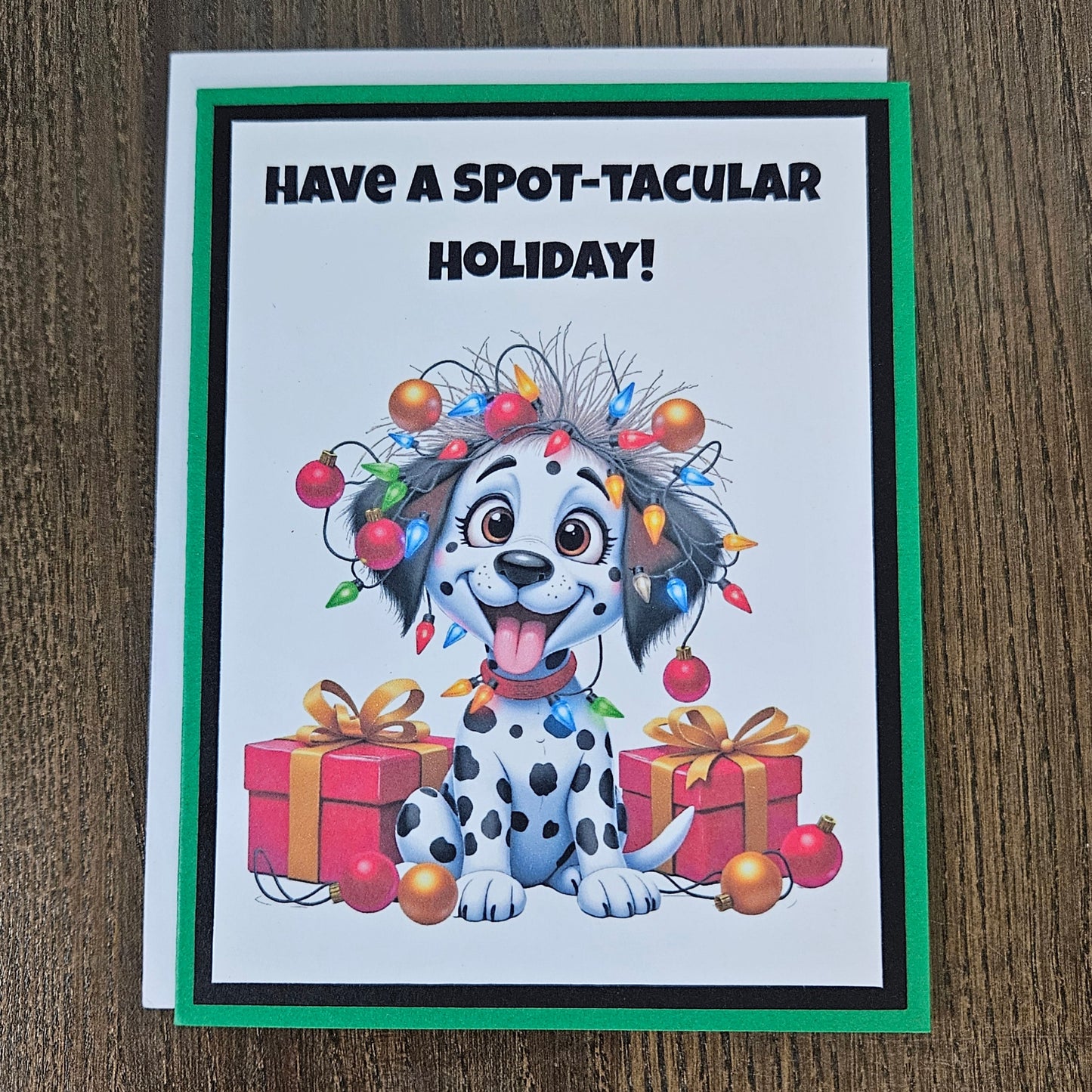 Front of a funny handmade A2 Christmas card featuring a Dalmatian puppy tangled in Christmas lights reading Have A Spot-Tacular Holiday.