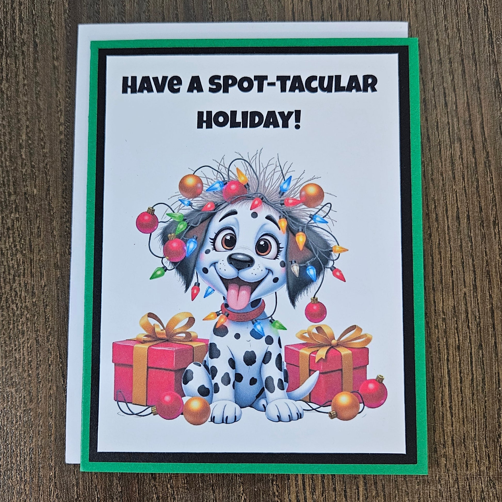 Front of a funny handmade A2 Christmas card featuring a Dalmatian puppy tangled in Christmas lights reading Have A Spot-Tacular Holiday.
