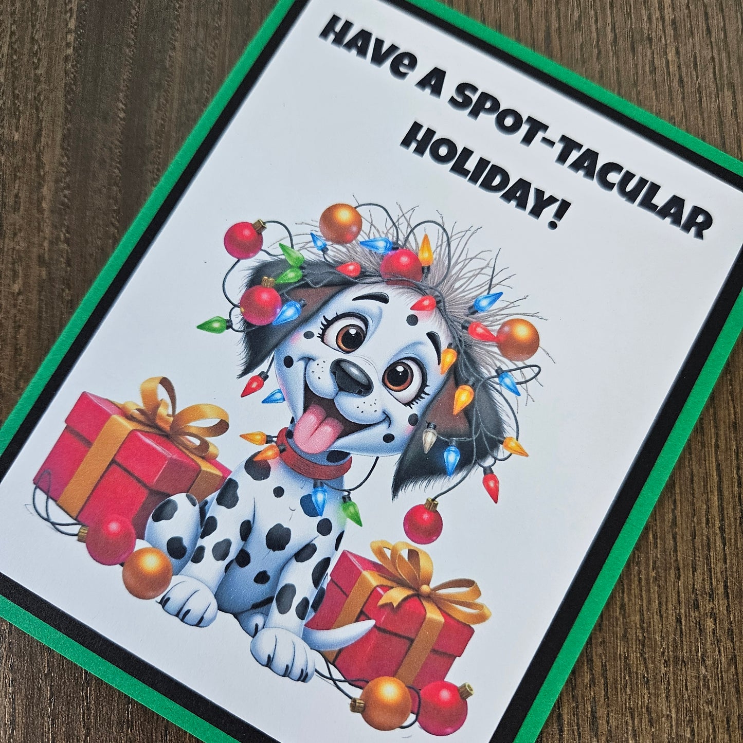 Front of a funny handmade A2 Christmas card featuring a Dalmatian puppy tangled in Christmas lights reading Have A Spot-Tacular Holiday.