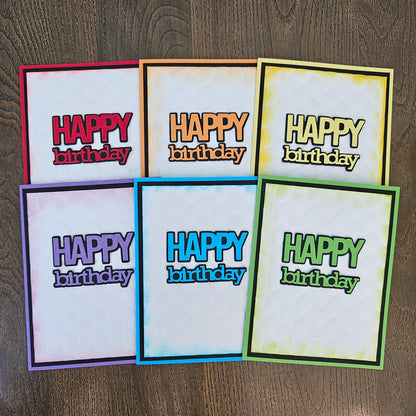 Six colorful 'Happy Birthday' greeting cards arranged in two rows on a dark wood background. The cards feature different border colors including red, orange, yellow, purple, blue, and green, with a white watercolor-textured background and bold retro-style text.