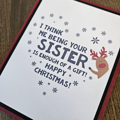 Close-up of funny sister Christmas message, red-nosed reindeer, and scattered snowflakes