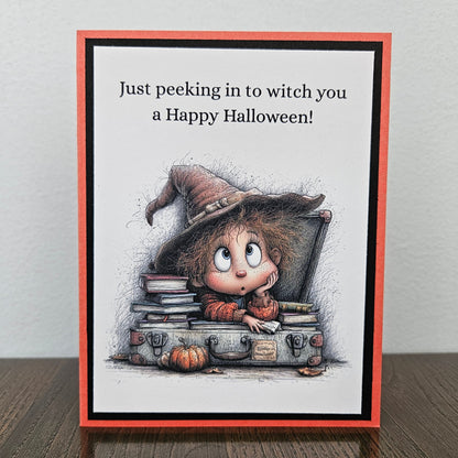 Handmade funny Halloween card with young witch peeking over spellbooks and a vintage trunk