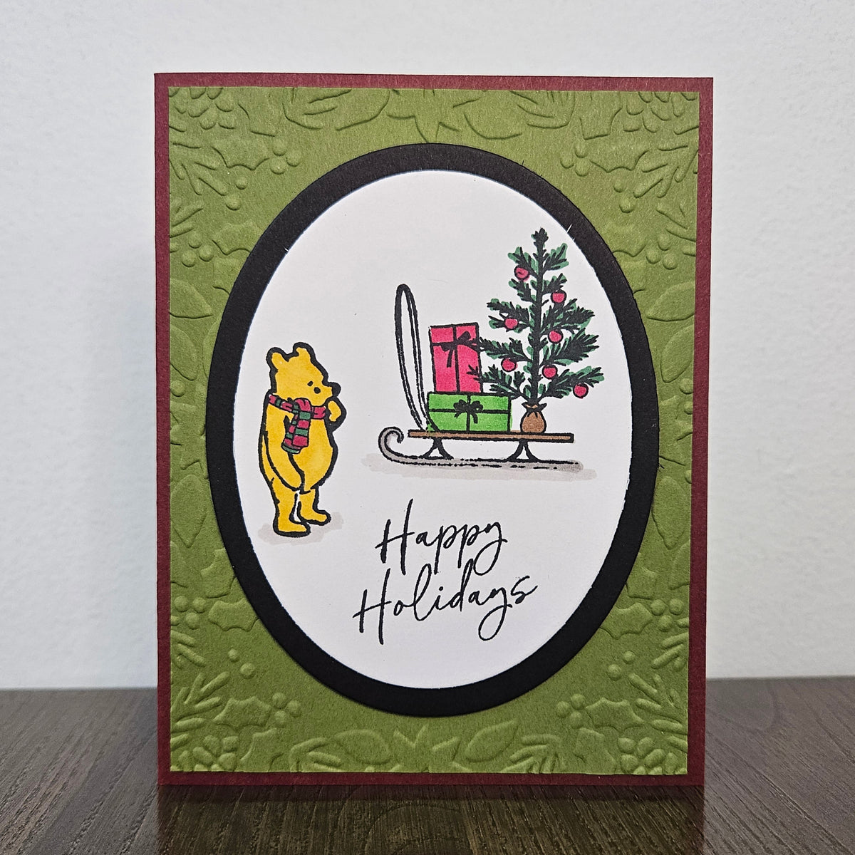 Handmade Winnie the Pooh Christmas card with Pooh beside a gift sled and Happy Holidays sentiment