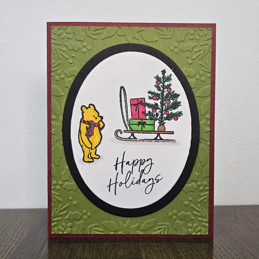 Handmade Winnie the Pooh Christmas card with Pooh beside a gift sled and Happy Holidays sentiment