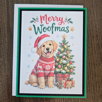 A Christmas greeting card featuring a golden retriever dog wearing a red Santa hat and red knit sweater, sitting beside a decorated Christmas tree. The card reads 'Merry Woofmas' in red and green lettering, with paw prints and snowflake accents.