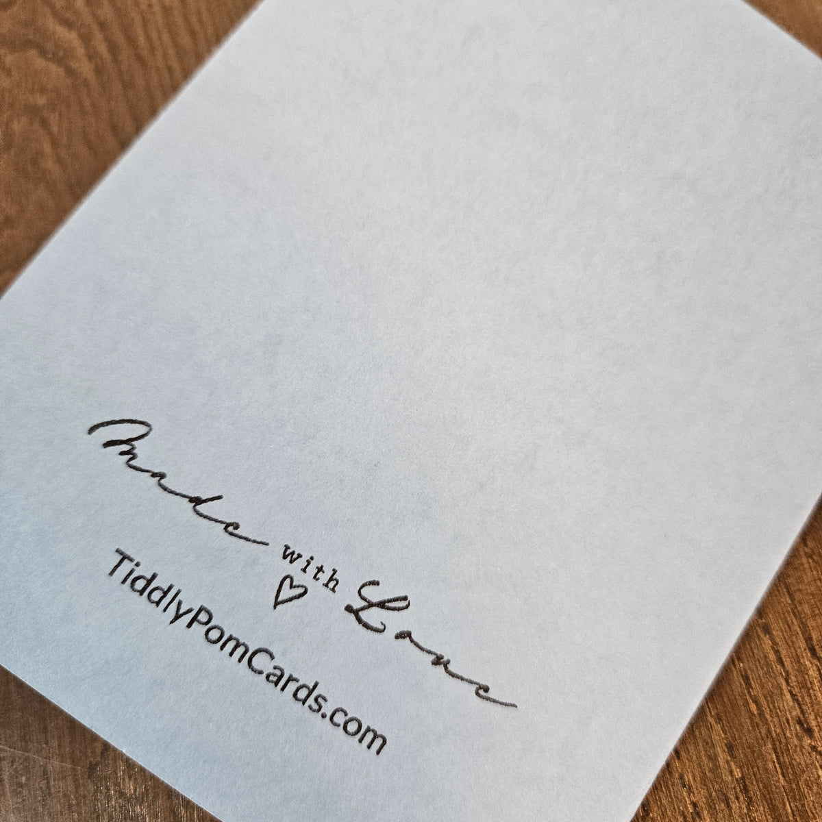 Back of the light-blue handmade Winter Solstice card, showing the handwritten maker’s mark, small heart, and TiddlyPomCards.com.