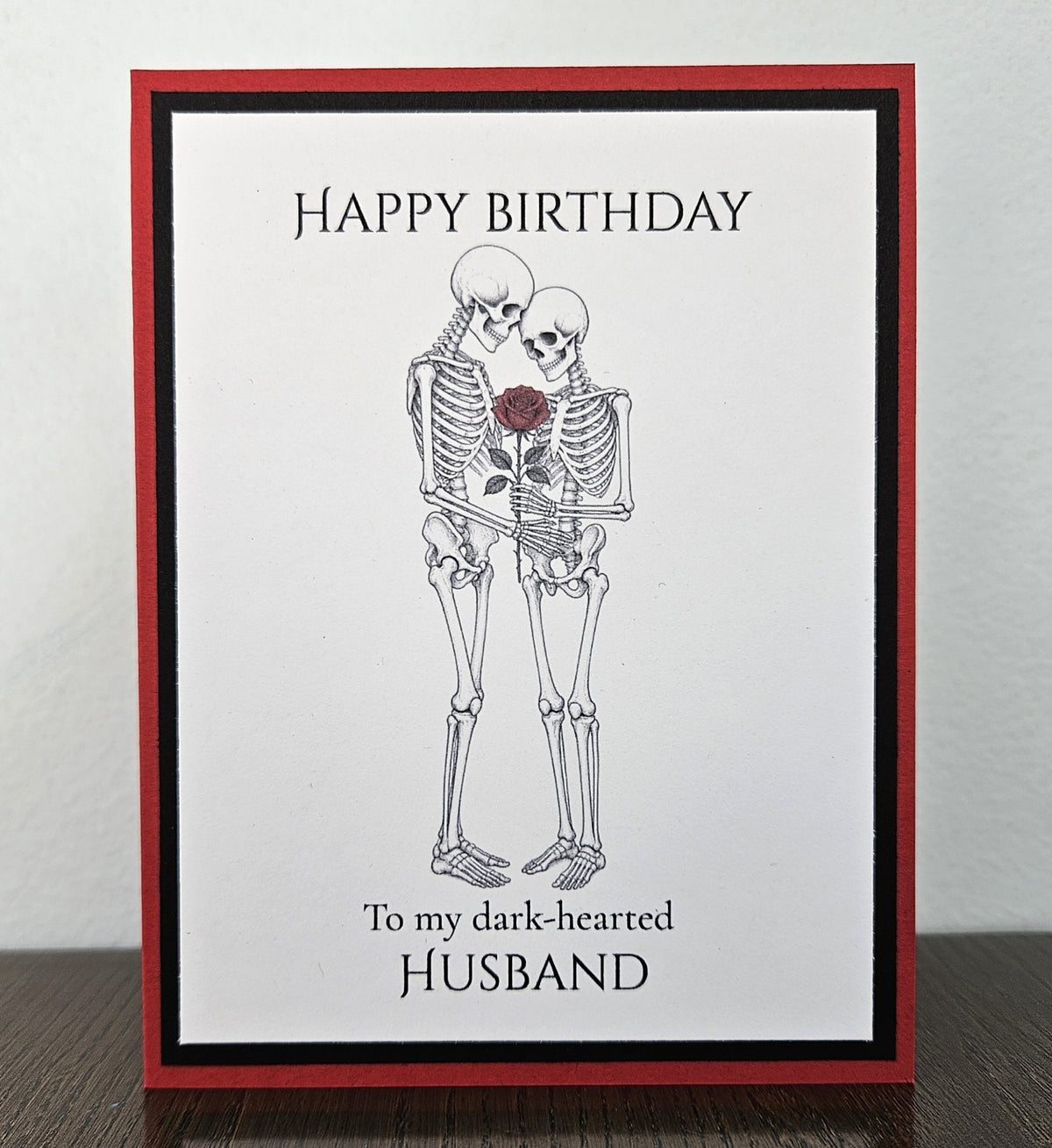 Handmade red and black birthday card with an embracing skeleton couple, red rose, and Happy Birthday to my dark-hearted husband wording.